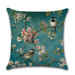 Cushion cover with a nature-inspired design featuring birds and blooming flowers on a teal background. The cushion cover is made of high-quality materials and is suitable for use in various home decor settings.