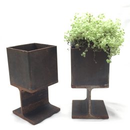 Industrial-style steel plant pots in a square shape with a minimalist design. The pots feature a dark, rustic finish and are suitable for displaying small plants or greenery.