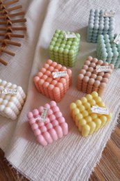  Colorful cube-shaped pillar candles in various pastel shades including pink, green, yellow, and blue. The candles have a textured, honeycomb-like pattern on the surface.
