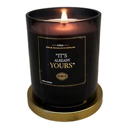 Scented candle with cedar and jasmine fragrance, part of the Manifest Collection. The candle has a black glass container with gold text that says "It's Already Yours".