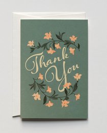 A green greeting card with the text "Thank You" surrounded by a floral wreath of orange and white flowers.
