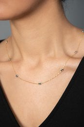 Delicate gold-toned necklace with small colored gemstones spaced evenly along the chain.