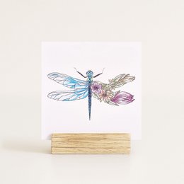 Colorful dragonfly illustration on a greeting card without an envelope. The card features a detailed, artistic rendering of a dragonfly with vibrant wings in shades of blue, purple, and brown.