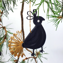 Black and gold decorative bird ornament in a box, made of natural materials.