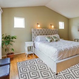 A modern, smokey grey kilim rug with a geometric Greek key pattern, suitable for use as a runner in a bedroom.