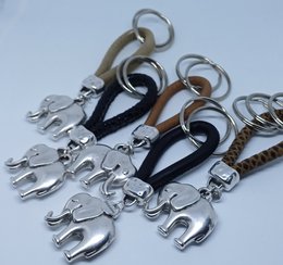 Leather keychain with elephant charm in black reptile, black matt, taupe brown, brown reptile, and ivory reptile finishes.
