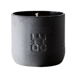 A matte black, sustainable scented candle in a upcycled water bottle with a 60-hour burn time. The candle has a floral and earthy fragrance.