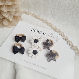  Festive night-themed hair ties in various shapes and colors, including black bows, white daisies, and star-shaped accessories.