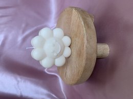 Flower-shaped white pillar candle on a wooden stand. Available in various colors including natural, pink, yellow, orange, green, turquoise, light blue, blue, gray, and purple.