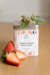 Organic loose leaf tea in a glass jar with a red and white label. The tea is light in color and appears to be a delicate, aromatic blend.