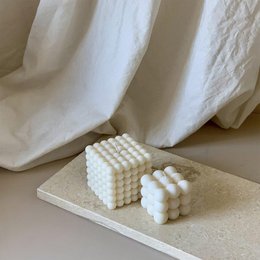 Cream-colored, cube-shaped wax candle with a bubble-like texture, suitable for home decor or as a gift.