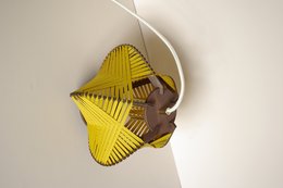 Mustard yellow table lamp with a unique geometric design featuring intersecting triangular panels and a dark brown base.