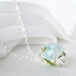 Delicate necklace with light turquoise glass flowers and a small charm. The necklace features a glass pendant with a floral design in shades of turquoise and green.