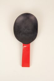  Black oval-shaped rice spoon with a red handle, designed for straining and serving rice.