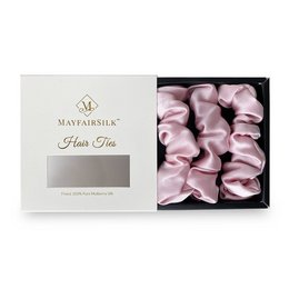 A set of three precious pink silk scrunchies in a gift box. The scrunchies have a soft, luxurious texture and are perfect for styling hair.
