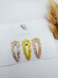Set of 3 colorful hair clips in spring-inspired designs, including a yellow, pink, and white glitter clip.