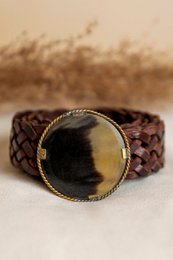 Small brown leather belt with a metal buckle, packaged in a polka dot gift box.