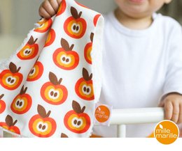 Colorful cuddle cloth with funky apple print, featuring a soft, cozy fabric and vibrant orange and red apple designs.