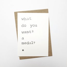 A sarcastic greeting card with the text "What do you want? A medal?" printed on it, suggesting the card is meant to be a humorous response to someone seeking praise or recognition.