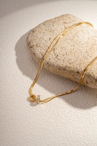 Die Doppelketten -Halskette kombiniert Einfachheit und Eleganz mit seinen beiden Ringen