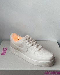  A round, tall, pearl-colored candle in the shape of an AF1 sneaker. The candle is available in small and large sizes, with scents like dark honey & tobacco, lime basil & mandarine, and unscented.