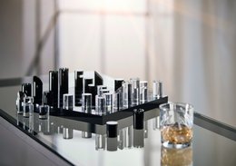 A black and silver chess game set with a modern, minimalist design. The game pieces are made of glass and metal, creating a sleek and sophisticated look.