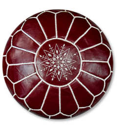 A round, burgundy-colored leather pouf with a decorative star-shaped pattern. The pouf appears to be made of high-quality leather and has a textured, intricate design.