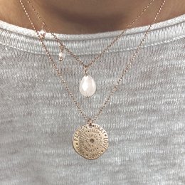 Rose quartz necklace with a flying charm and pearl pendant on a delicate gold chain.