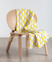 Throw blanket with yellow and white diamond pattern, made of soft, cozy material.