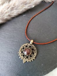 Elegant gold-toned pendant necklace with intricate filigree design and a central amber-colored gemstone, perfect for adding a touch of warmth and joy to any outfit.