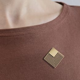 Graphic golden rhombus brooch with a modern, minimalist design.