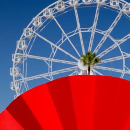  Red opaque hand fan with a radial design.
