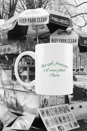 A white ceramic mug with the text "A LA VIE L'AMOUR" printed in red on the side. The mug is being held by a person wearing a plaid shirt, suggesting this is a decorative or novelty mug.