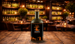  Extra virgin olive oil in a glass bottle with a rustic wooden table and blurred bar background.
