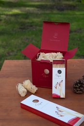 Long, red scented matches in a decorative box with a pine cone accent.