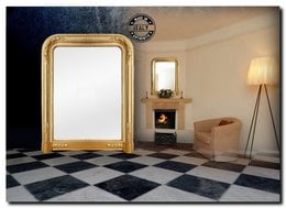 Ornate gold-framed mirror with a decorative console table and lamps in a stylish, modern interior.