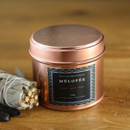 Sage and musk scented candle in a round copper-colored tin container.