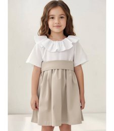 A white ruffled top with a beige skirt and a large bow at the waist. The dress has a classic, elegant style suitable for a young girl.