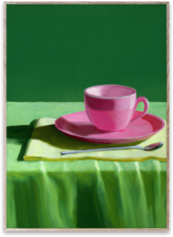A vibrant pink teacup and saucer set on a green cloth, with a modern abstract artwork in the background.