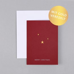 A red Christmas card with gold foil stars and the text "Merry Christmas" printed on it.