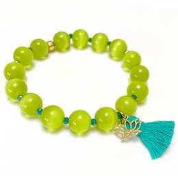 Green beaded bracelet with cat's eye charm and tassel accent, suitable for casual or boho-inspired outfits.