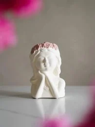 White ceramic vase with floral details and a round opening.