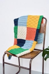Colorful patchwork blanket made of soft merino wool in a variety of patterns and textures, suitable for use as a cozy throw or decorative accent.