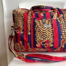 Large travel bag with a vibrant, patterned design featuring a tiger motif and bold colors. The bag is made of a durable, woven material and has a spacious interior suitable for weekend getaways.