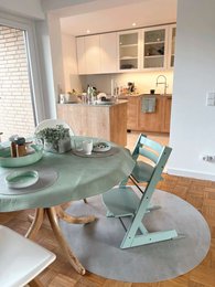 A round, mint-colored protective mat for a baby highchair, made of oak wood, ivory coast, nordic pine, or cloudy gray materials.