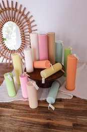  Tall, round, ribbed candles in a variety of pastel colors including pink, yellow, orange, mint, and green. The candles are displayed on a wooden stand.