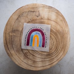 Colorful rainbow-shaped iron-on patch with polka dot border, suitable for decorating clothing or accessories.