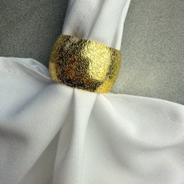 Gold napkin ring with a hammered texture.