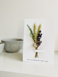 Dried lavender and yellow flowers in a vase, with a handwritten note.