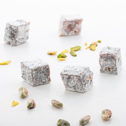 Turkish delight classic honeymoon, a gummy candy product. The image shows several cubes of Turkish delight, a traditional Middle Eastern confection made with sugar, cornstarch, and flavored with rose water or lemon. The cubes have a powdery coating and are surrounded by pistachio nuts. This product appears to be a classic or traditional variety of Turkish delight.